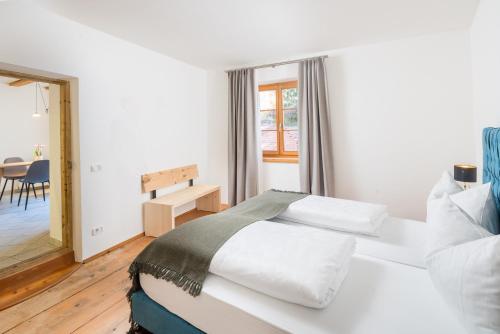 a white bedroom with a bed and a table at Hotel Greif in Malles Venosta