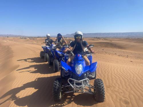 a group of people riding atvs in the desert at La Perle Du Drâa in Zagora