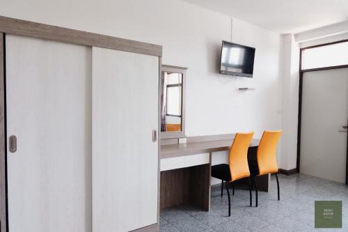 a room with a desk with chairs and a tv at KHAO KIEOW Hotel โรงแรมเขาเขียว in Ban Mai