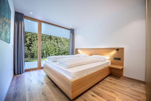 een slaapkamer met een groot bed en een groot raam bij Greva Apartments 1 in Santa Cristina in Val Gardena