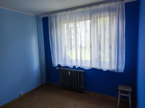 a blue room with a window and a radiator at Apartament na Wyszyńskiego - mieszkanie w centrum Myszkowa dla firm i nie tylko in Myszków