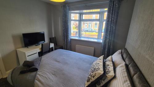 a bedroom with a bed and a television and a window at Ravenhill Townhouse Belfast in Belfast
