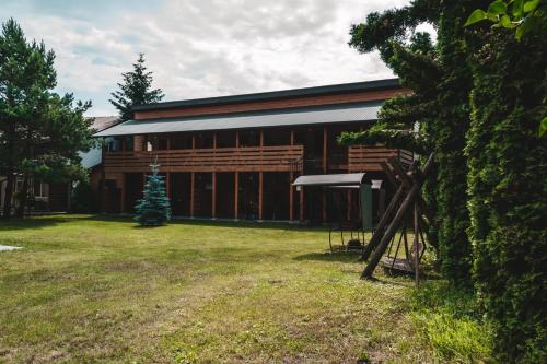 a large wooden building with a tree in the yard at Sonyachni bungalo in Melʼniki