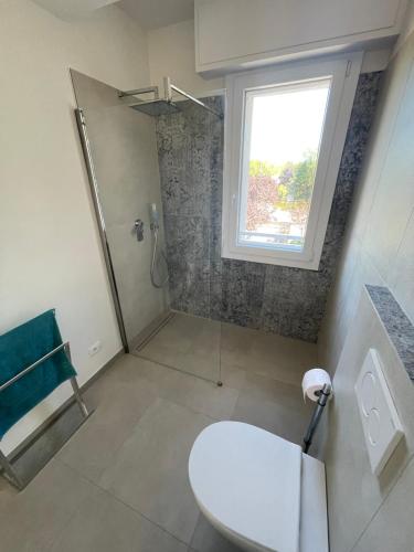 a bathroom with a toilet and a shower with a window at Villa Primule Cattolica in Cattolica