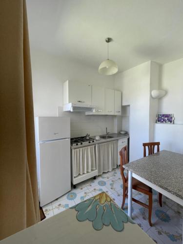 a kitchen with white cabinets and a table with chairs at Appartamento e piscina condivisa ISIDE in Ischia