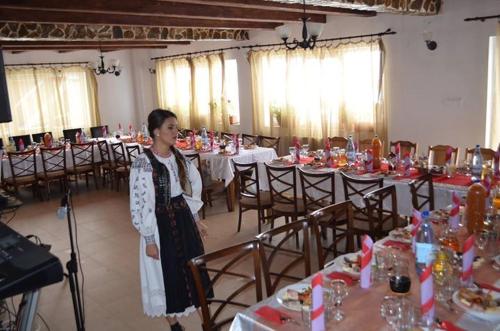 a woman standing in front of a room with tables at Pensiunea Popasul Iancului in Mărişel