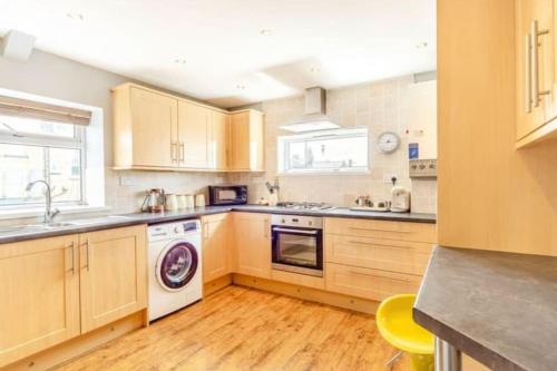a kitchen with wooden cabinets and a washer and dryer at Bewick House Large three bedroom Sleeps upto six in Newbiggin-by-the-Sea