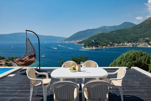 a table and chairs on a balcony with a view of the water at Villa Bojana in Tivat