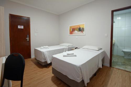 a hotel room with two beds and a bathroom at Fênix Hotel Campinas in Campinas