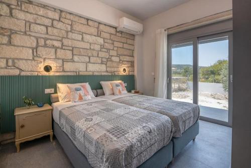 a bedroom with a large bed and a stone wall at Gramvousa's Hidden Gem in Áyios Yeóryios