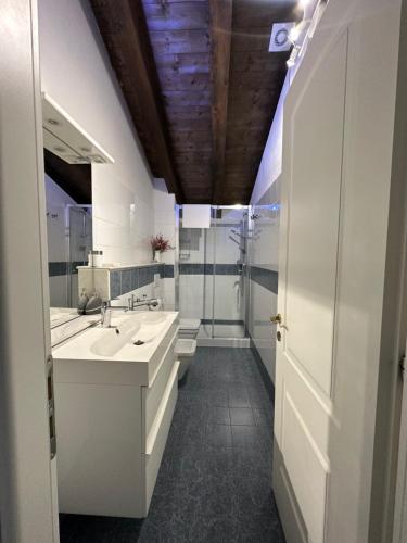 - une salle de bains blanche avec deux lavabos et une douche dans l'établissement Piuma apartment, à Gorizia