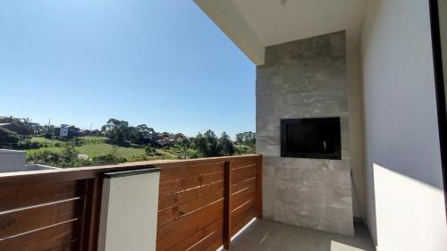 a balcony with a television and a stone wall at Suítes do Vale - Praia do Rosa in Imbituba
