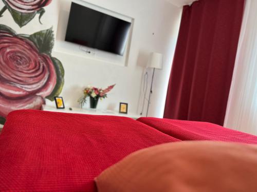 a bedroom with a red bed with a tv on the wall at Rose No 4 in Friedrichshafen