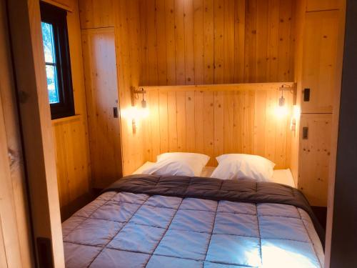 a bedroom with a bed in a wooden wall at Lodges du Ushuaïa Villages Camping les 4 Saisons in Grane