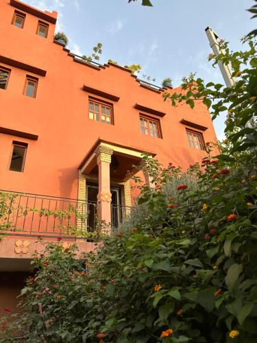 un bâtiment orange avec un balcon et quelques buissons dans l'établissement Ourika lodge the healing place, à Tafza
