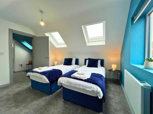 two beds in a room with blue walls and skylights at Modern 3 Bedroom House, Sleeps 6 - Free Parking & Garden - Opposite Racecourse, Near City Centre & Hospital in Doncaster