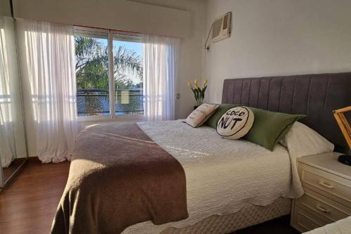 1 dormitorio con cama con almohadas y ventana en La Casita de Guale en Gualeguaychú