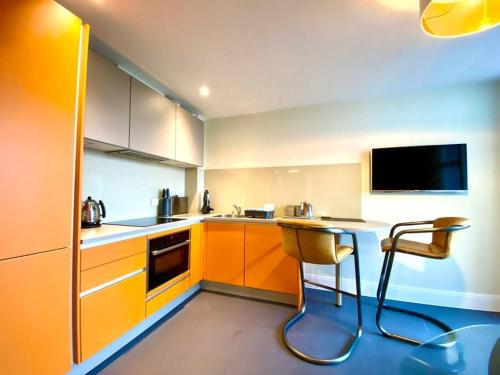 uma cozinha com armários laranja e uma mesa e cadeiras em Incredible Apartment - Amazing Location - Free Parking & WiFi! em Poole