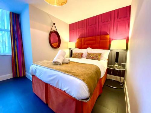 um quarto com uma cama grande e uma cabeceira vermelha em Incredible Apartment - Amazing Location - Free Parking & WiFi! em Poole