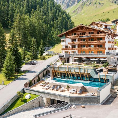 a hotel in the mountains with a swimming pool at Das Homann in Samnaun