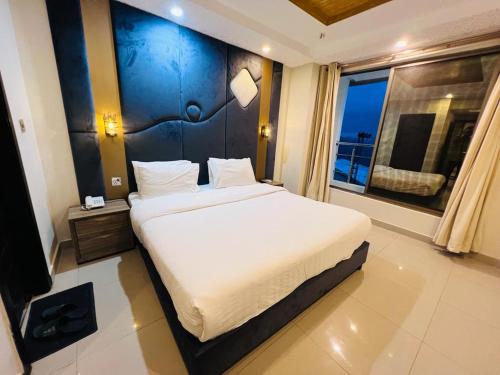 a bedroom with a large bed and a large window at Shelton's Suites Bhurban in Bhurban