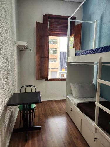a small room with a bunk bed and a table at Fujima Hostel in Sao Paulo