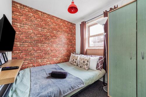 a bedroom with a brick wall and a bed and a desk at 2BED Garden house w/Hot Tub, Sauna & Cinema room in London