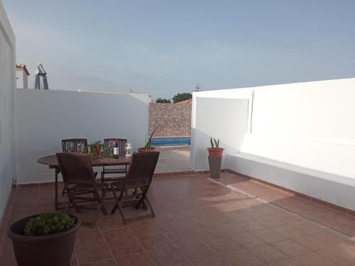 un patio con tavolo, sedie e parete bianca. di Casa tomas C a Villaverde