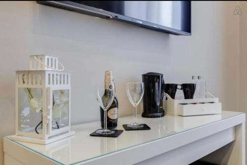 un bancone bianco con bicchieri da vino e bottiglie sopra di DGS APARTHOTEL a Trapani