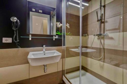 トラーパニにあるDGS APARTHOTELの洗面台とガラスのシャワーを備えたバスルーム