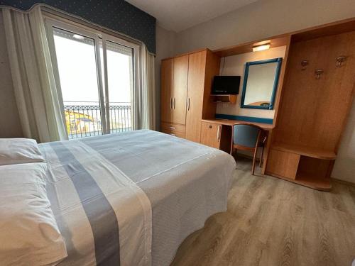 a hotel room with a bed and a desk with a mirror at Hotel Costa Verde in Pineto