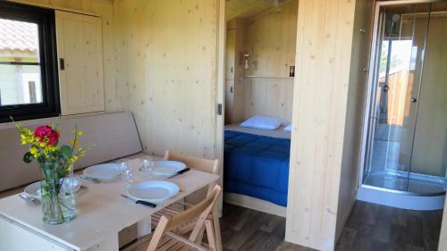 Lodges du Camping les 4 Saisons في Grane: غرفة صغيرة مع طاولة وسرير
