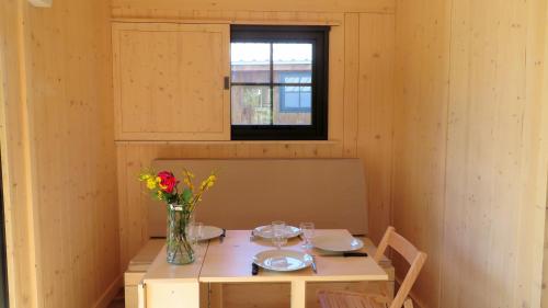 a small room with a table with a vase of flowers at Lodges du Ushuaïa Villages Camping les 4 Saisons in Grane