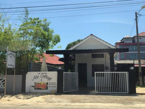 a white building with a sign in front of it at Abe cottage in Kuala Besut