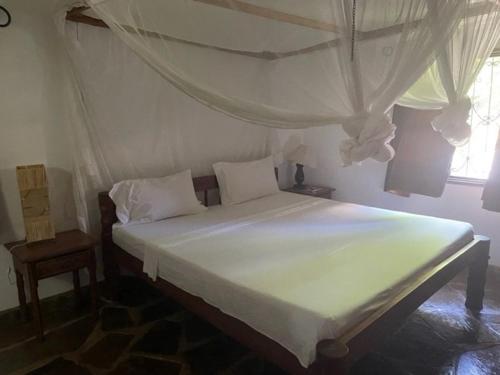 a bedroom with a white bed with a canopy at Lion Garden Villa 6 in Malindi