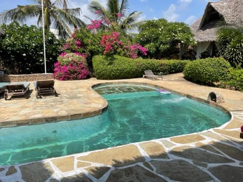 馬林迪的住宿－Lion Garden Villa 6，庭院内的游泳池,带椅子和鲜花