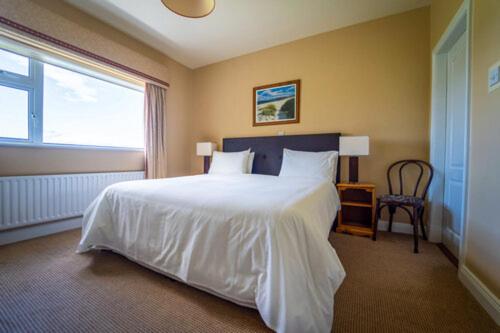 a bedroom with a large white bed and a window at Bambury's Guesthouse in Dingle