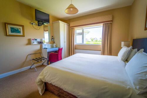 a bedroom with a large white bed and a window at Bambury's Guesthouse in Dingle