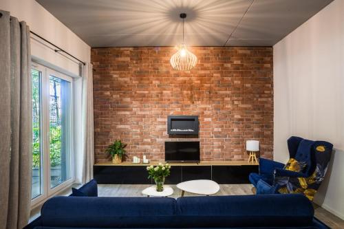 a living room with a blue couch and a brick wall at Apartament Parkowy przy Stadionie Śląskim Katowice Chorzów in Chorzów