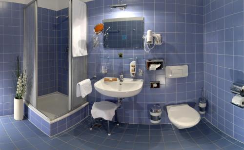 Zeithain的住宿－Hotel Moritz an der Elbe，蓝色瓷砖浴室设有水槽和卫生间