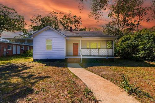 a small white house in a yard with a driveway at Beachy Central, Near Beach, 2 King Beds, Crib, Huge Private Yard, Patio, Porch, BBQ, & Firepit in Myrtle Beach