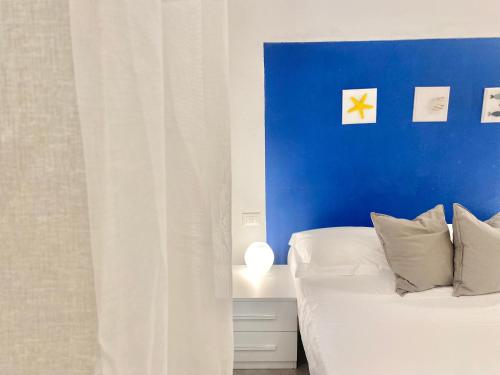 a room with two beds and a blue wall at Alla Casa Rosa al Mare, Central Seafront Stay, Air Conditioning, Wi-Fi, the Ideal Choice for a Relaxing and Exciting Coastal Escape, with available on request at 20,00 euro per night Private Garage, Welcome kit Priority, Prosecco and Canestrelli in Rapallo