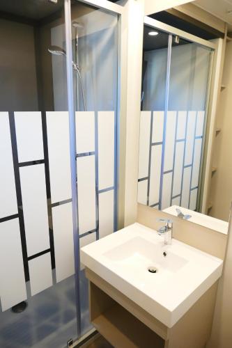 a bathroom with a sink and a mirror at Escales Voyages Cottage des Dunes - Chalet de 49m2 climatisé - 6 personnes in Jullouville-les-Pins