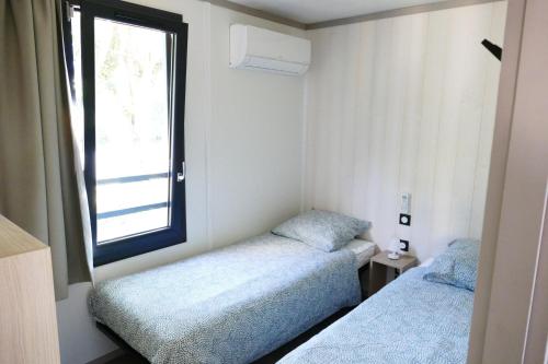 two beds in a small room with a window at Cottage des Dunes - Chalet de 49m2 climatisé - 6 personnes in Jullouville-les-Pins