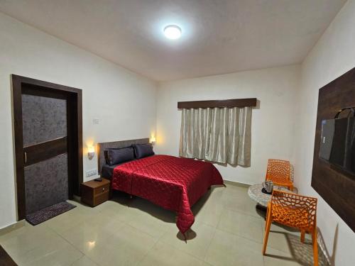um quarto com uma cama vermelha e uma televisão em July17 residency em Kodaikanal