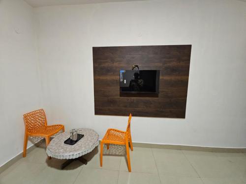 een kamer met 2 stoelen, een tafel en een tv bij July17 residency in Kodaikānāl