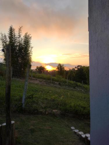 a sunset in a field with a fence at Suítes do Vale - Praia do Rosa in Imbituba