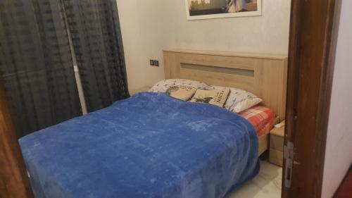 ein kleines Schlafzimmer mit einem Bett mit einer blauen Decke in der Unterkunft Appartement lala fatima in Fès