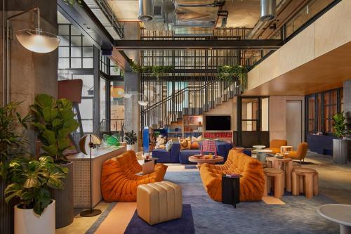 a lobby with orange chairs and tables in a building at Moxy Sydney Airport in Sydney