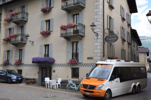 een oranje en witte bestelwagen geparkeerd voor een gebouw bij Meublé Albergo Dante in Bormio